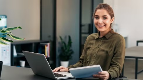 Person with laptop open and notepad in hand